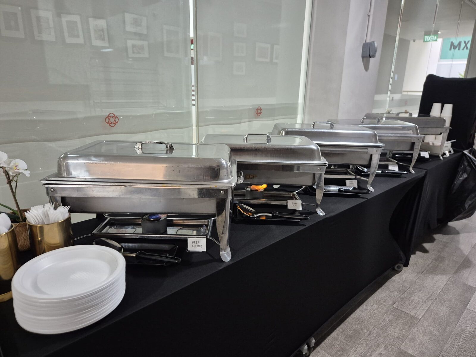 A line of labelled chafing dishes at a Sabar Menanti office catering